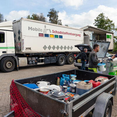 Ein Bürger gibt seine Farben und Lacke bei den Mitarbeitern der mobilen Schadstoffsammlung auf dem LKW ab.