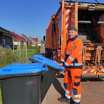 Zwei Blaue Tonnen werden von dem Müllwerker Jens Stamm zum Müllfahrzeug gebracht.