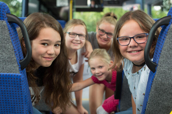 Fünf Mädchen sitzen in einem Bus und lächeln