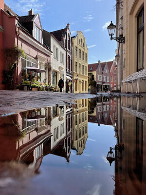 Blick in die Leeraner Altstadt, in einer Pfütze spiegeln sich die Häuser.