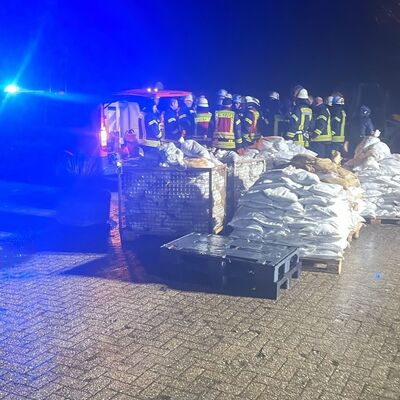 Feuerwehrleute in Hollen mit Paletten mit Sands&auml;cken