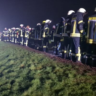 Menschenkette: Feuerwehrleute in Hollen auf dem Deich