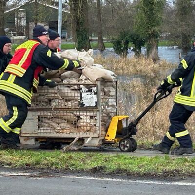 Feuerwehrleute transportieren Sands&auml;cke.