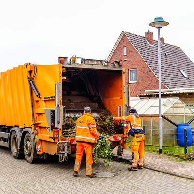 Müllwerker beladen das Müllfahrzeug mit Sträuchern