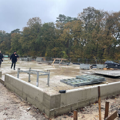 Baustelle mit frisch gegossenem Fundament und einzelnen Metallrahmen