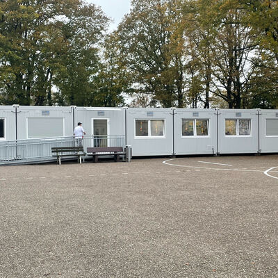 Container mit T&uuml;ren und Fenstern auf einem Schulhof mit Basketballkorb