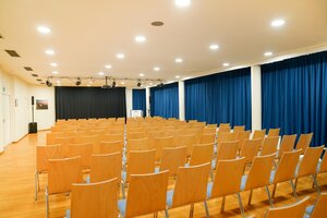 St&ouml;rtebeker Saal mit Sitzm&ouml;glichkeiten. Im Hintergrund blaue Gardinen