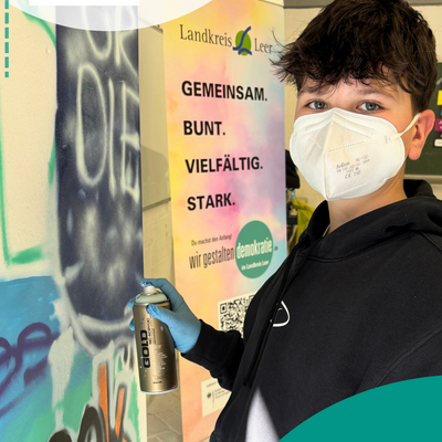 Junge mit Maske spr&uuml;ht auf Wand