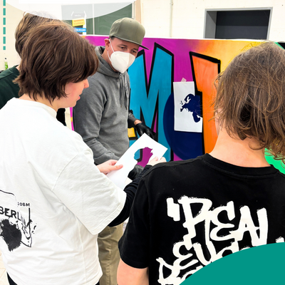 Gruppe bespricht sich vor einer Wand mit Graffiti