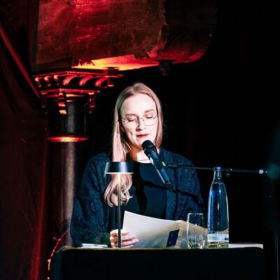 Leonie Plaar wie sie an einem Pult steht und vorliest