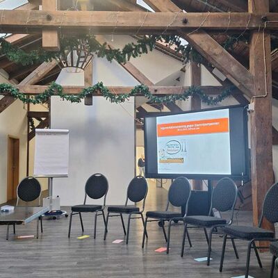 Raum des Workshops, St&uuml;hle im Halbkreis aufgestellt, im Hintergrund eine Leinwand