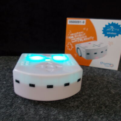 Thymio-Ger&auml;t und Verpackung im Hintergrund