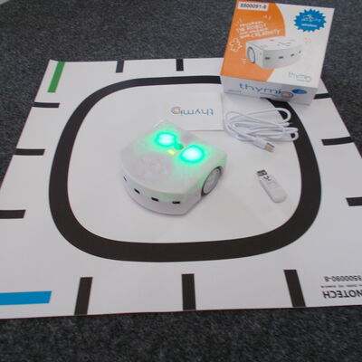 Thymio mit der gesamten Ausstattung (Matte, Aufladekabel und Verpackung)